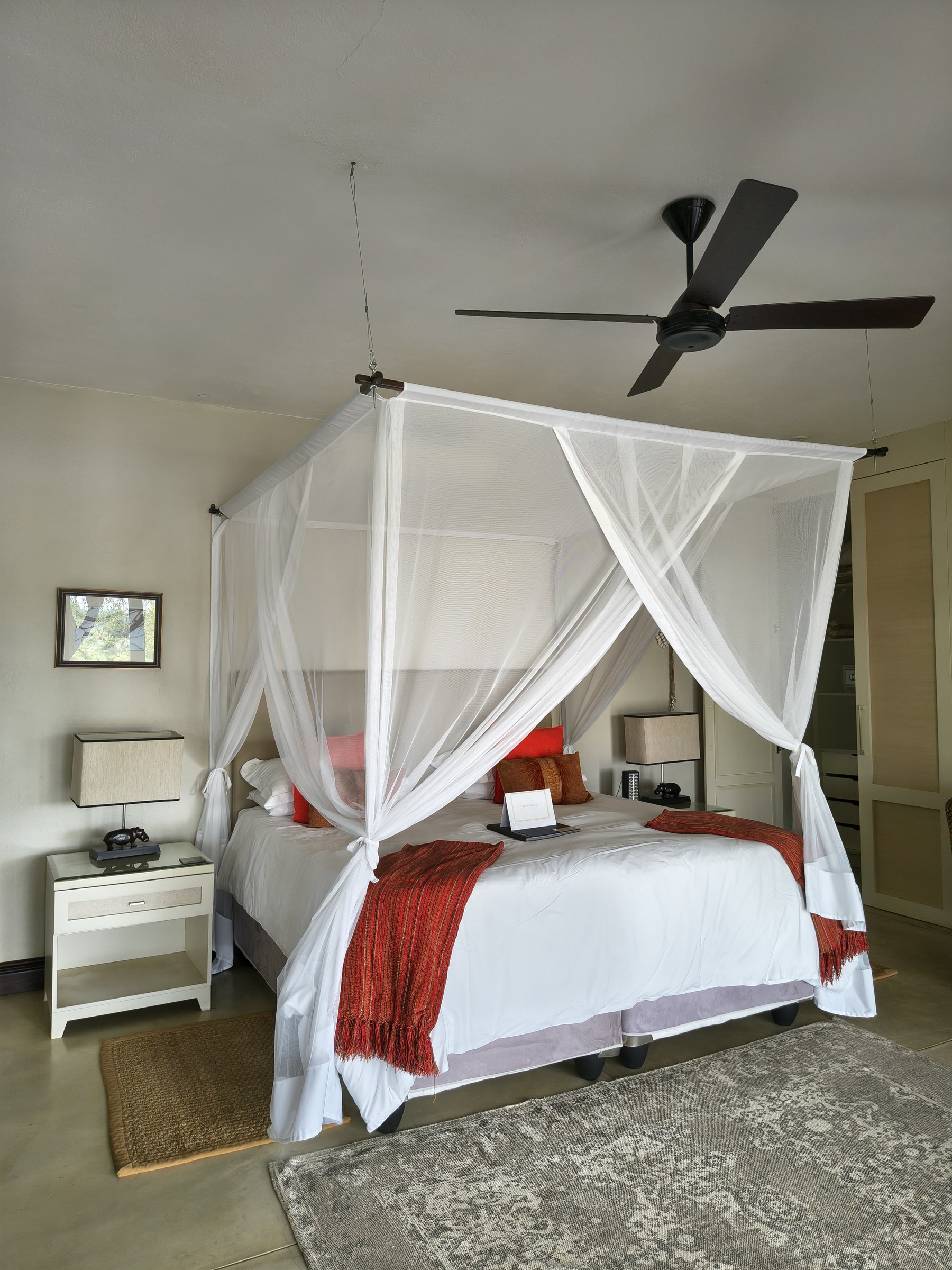 A suite bedroom with mosquito-net draped bed and warm accents